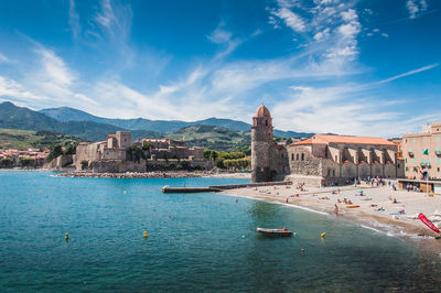 Panoramic view of sea and buildings against blue sky