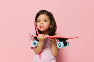 Portrait of cute girl with eyes closed against pink background