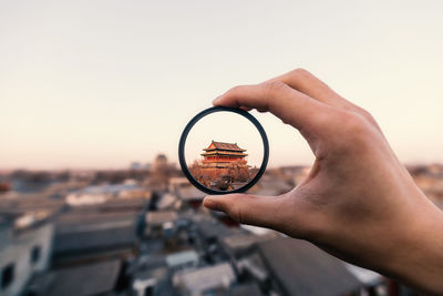 Cropped hand holding magnifying glass against white background