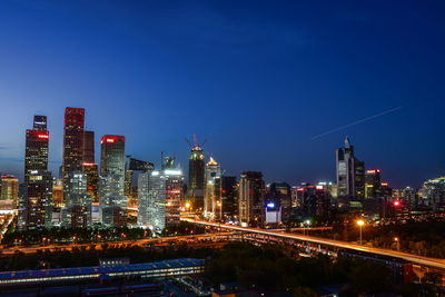 Illuminated buildings against clear blue sky