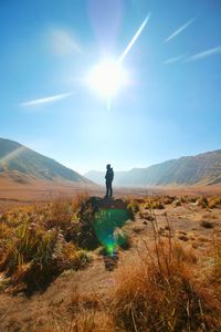 Silhouette man standing on field against bright sun