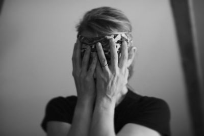 Close-up of woman covering face with hands at home