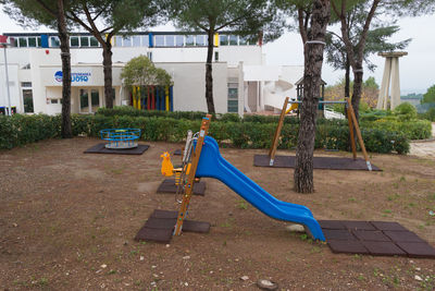 Empty bench in park against building