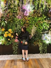 Full length of young woman walking on footpath amidst plants