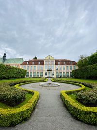 Footpath by garden against sky