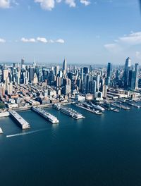 Aerial view of city buildings by sea against sky