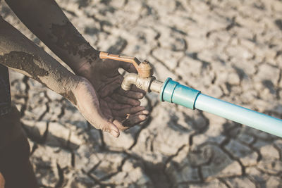 High angle view of hand by tap on barren field