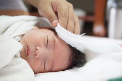 Close-up of cropped hand touching baby