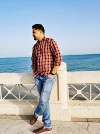Full length of boy standing at beach against sky