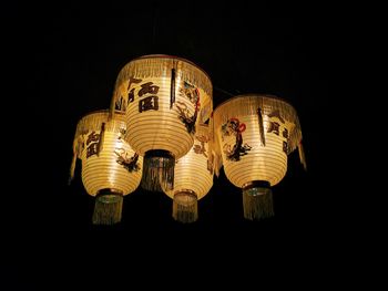 Low angle view of illuminated lantern hanging against black background