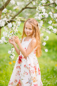 Portrait of woman standing by flowering plants