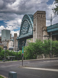 Road by bridge and buildings against sky