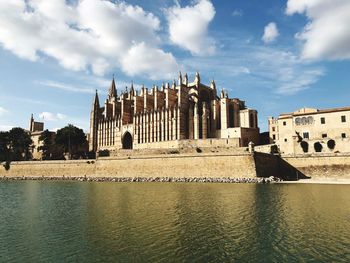 Historic building by river against sky in city