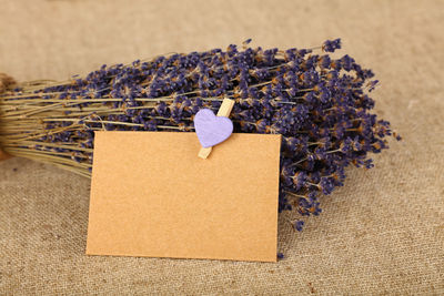 Close-up of blank cardboard with heart shape and flowers on jute