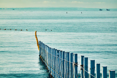 Wooden posts on beach by sea against sky