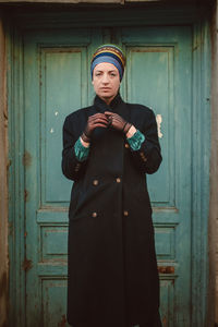 Portrait of young man standing against door