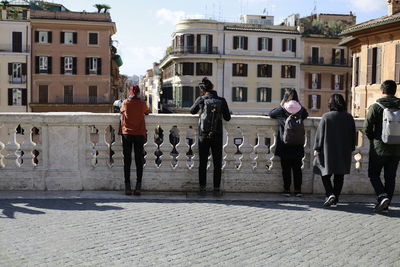 Rear view of people standing in front of buildings