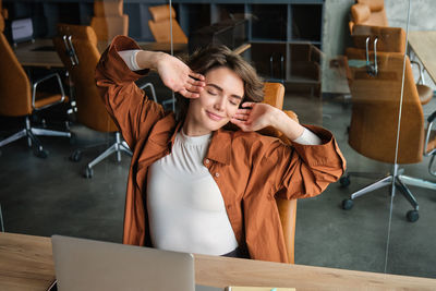 Portrait of young woman using mobile phone while sitting in classroom