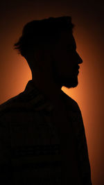 Close-up portrait of silhouette man against orange sky