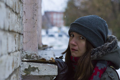 Close-up portrait of young woman by wall