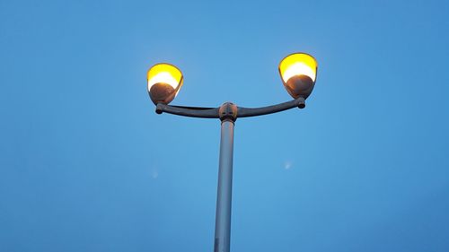 Low angle view of street light against blue sky