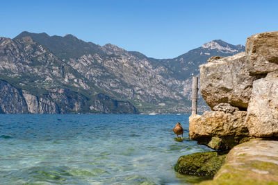 Scenic view of sea and mountains against clear blue sky