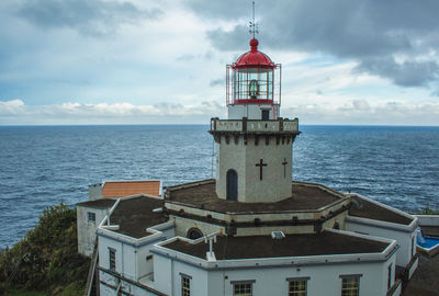 Lighthouse amidst sea and buildings against sky