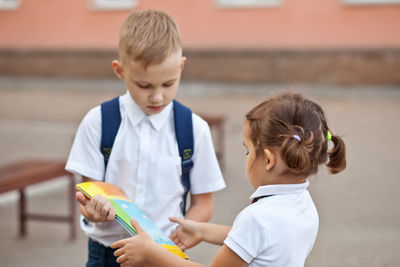 Boy giving books to girl outdoors