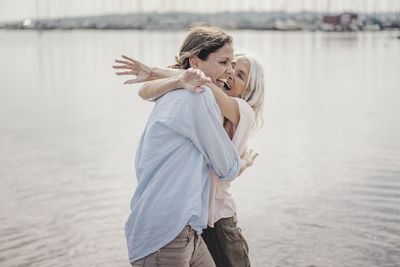 Mother and daughter spending a day at the sea, laughing and embracing