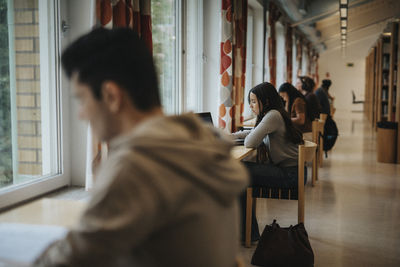 Students studying at table in library of university