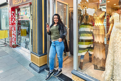 Portrait of smiling young woman standing at store