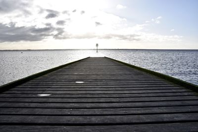 Jetty leading towards sea against sky