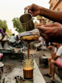 Cropped hands of male vendor preparing tea at market stall