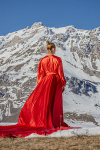 Rear view of woman standing on snowcapped mountain