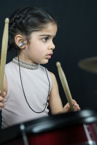 Girl wearing hearing aid while playing drum against wall