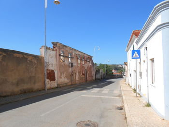 Street amidst buildings against clear blue sky