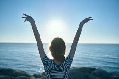 Rear view of woman standing in sea against clear sky