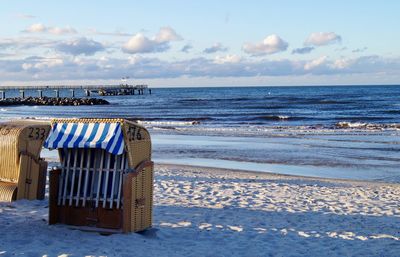 Hooded beach chair on shore against sky