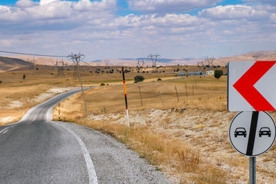 Road sign on field against sky