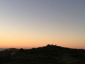 Silhouette built structure on land against clear sky during sunset