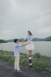 Rear view of people standing on shore against sky