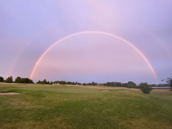Scenic view of rainbow over field against sky