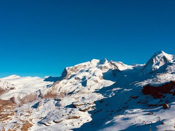 Scenic view of snowcapped mountains against clear blue sky