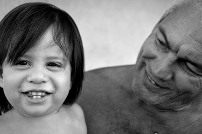 Portrait of cheerful boy with grandfather against wall