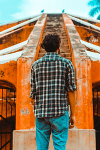 Rear view of man standing against built structure