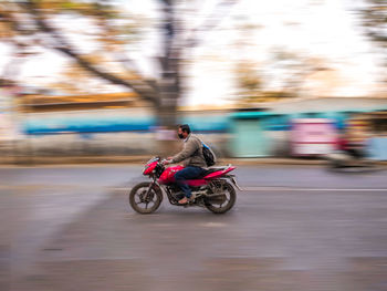 Blurred motion of man riding motorcycle on road