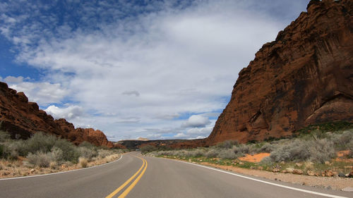 Road leading towards mountains against sky