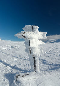 Snow covered field against blue sky