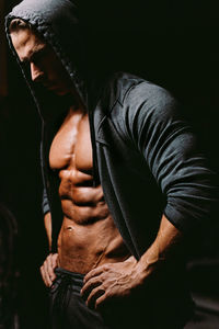 Man wearing hood standing in darkroom