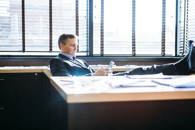 Businessman using mobile phone while relaxing in office